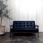 黒い二人掛けソファと白い板壁