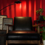 赤いカーテンの前に黒い椅子と雑貨